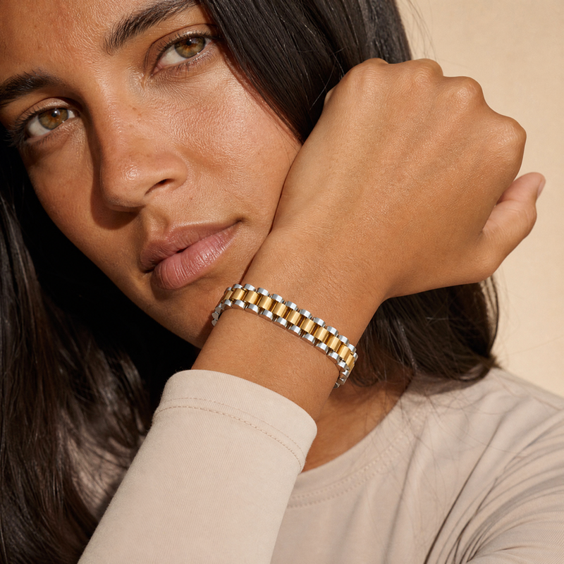 Two-tone gold and silver watch link bracelet styled on a wrist tucked beneath the chin