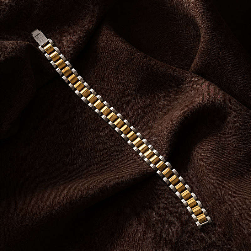 Gold and silver bracelet on a brown fabric background Two-tone watch link bracelet laid flat on dark brown linen, fold-over clasp visible