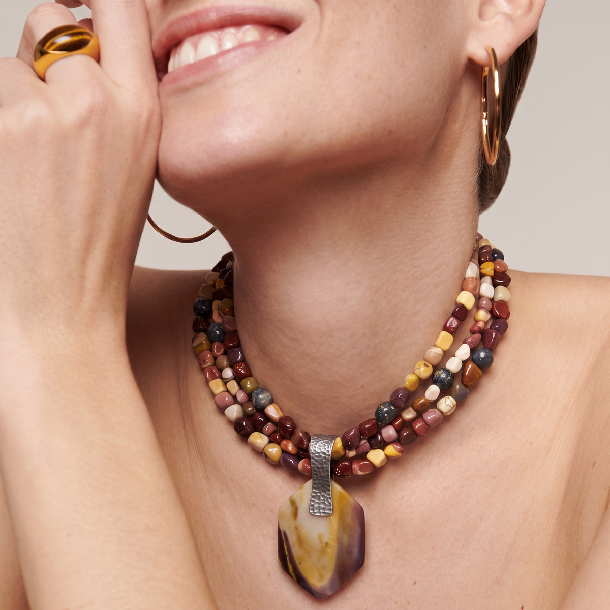 Mookaite jasper three-strand pendant necklace worn by a smiling model
