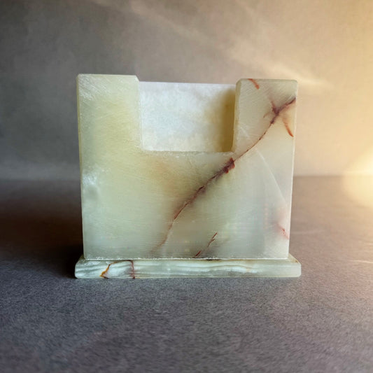 Square stone coaster holder in ivory and amber onyx with natural rust veining, shown at an angle.