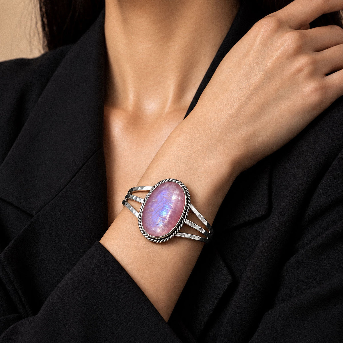 Pink moonstone cuff bracelet in sterling silver, worn on the wrist with a black blazer
