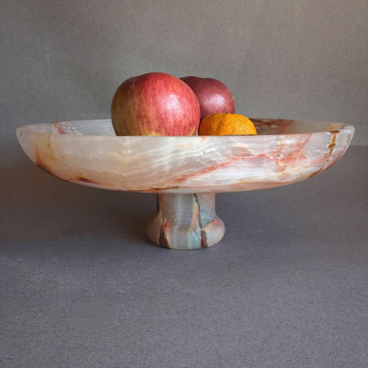 pink onyx Decorative stone pedestal with fruits on a gray background