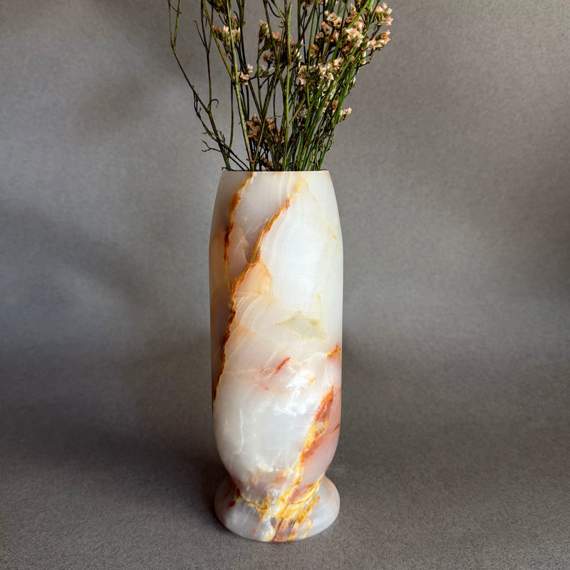 Marble-patterned onyx white honey vase with dried flowers on a gray background