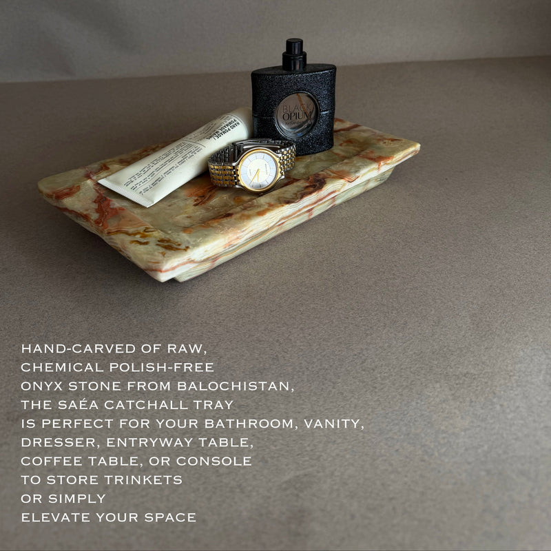 Decorative stone tray with a watch and perfume bottle on a gray background
