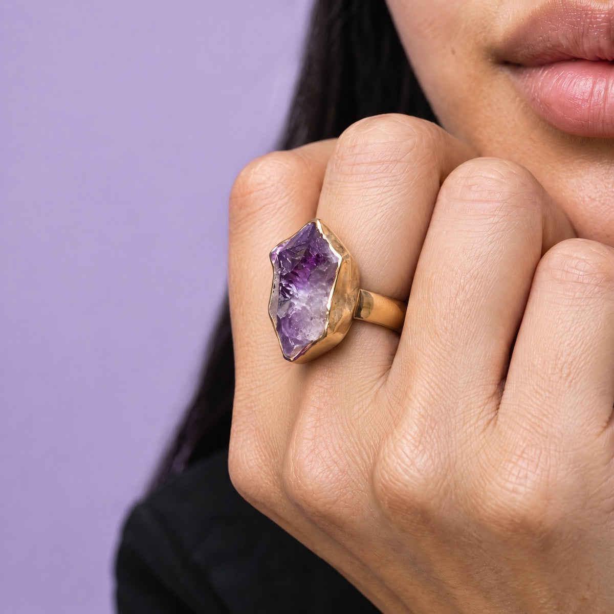 Raw pale lavender amethyst statement ring in a gold bezel, worn on a hand held to the chin