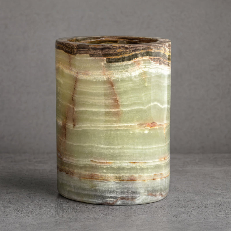 Hand-carved green onyx vessel in sage, jade, and ivory with rust veining and a deep brown banded rim on a neutral gray background