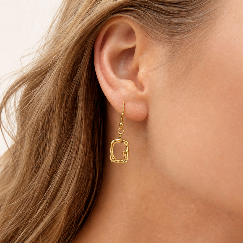 molten Gold sculptural earring worn by a person with light brown hair on a neutral background