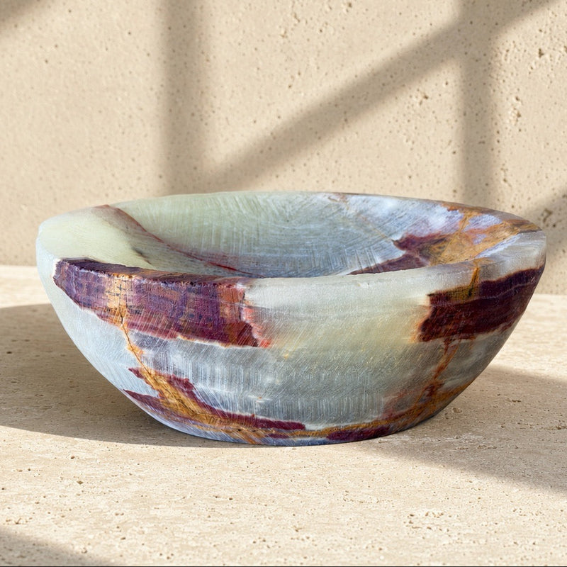 top-down view of a hand-carved onyx bowl in sage, cream, and burgundy, showing the crosshatch carving and rust veining inside the bowl.