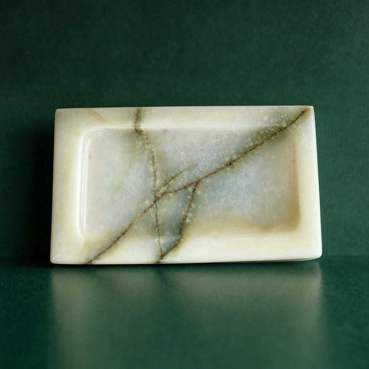 Sage green onyx catchall tray seen from above, pale ivory drifts and thin honey veining running the length of the stone.