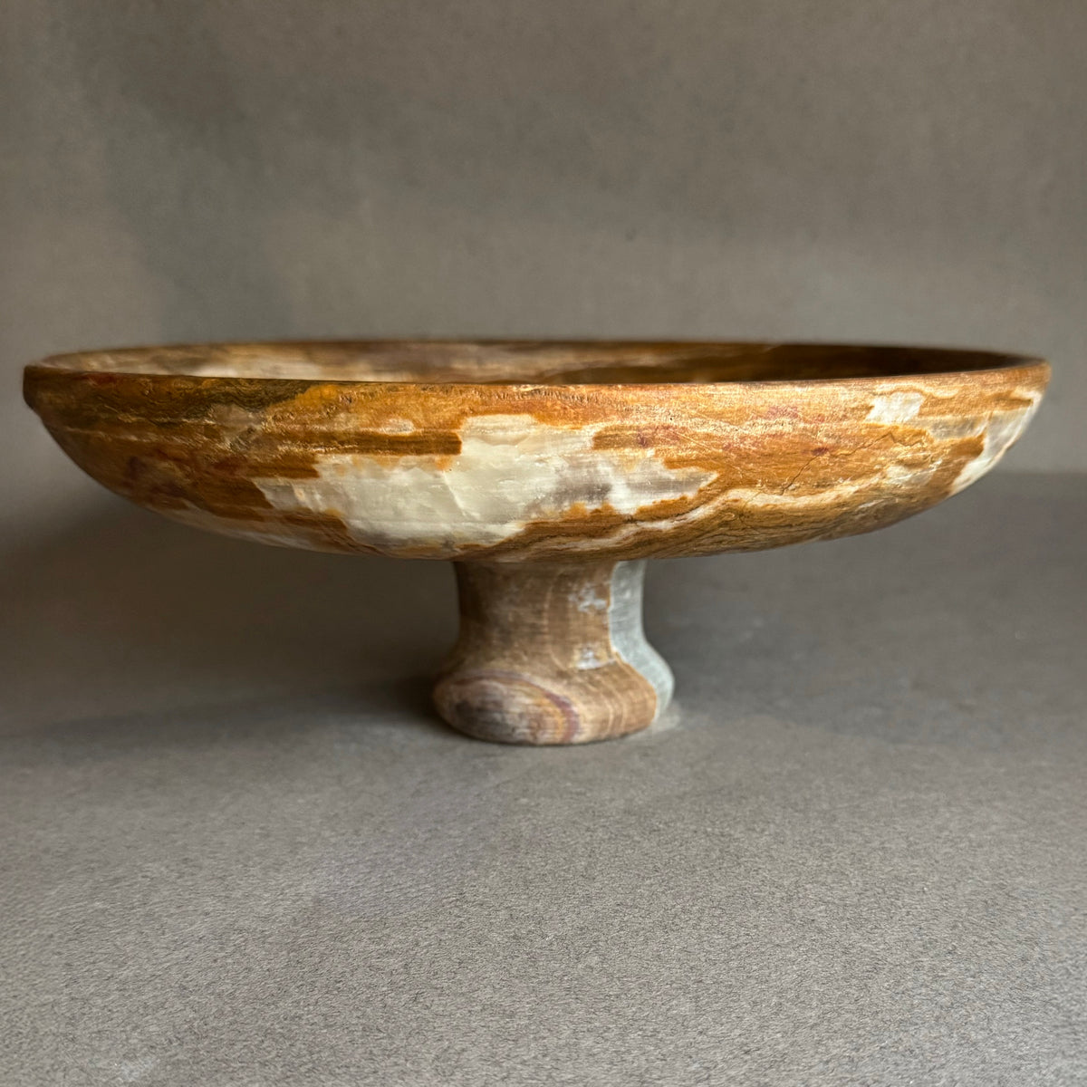 Hand-carved onyx pedestal bowl with cream, honey, and walnut veining, wide shallow form and pedestal base, natural stone fruit bowl and centerpiece.
