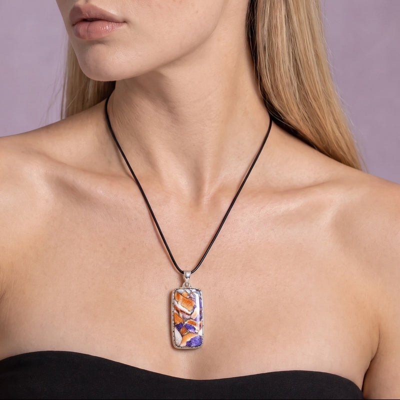 Spiny oyster, lapis and turquoise mosaic inlay pendant in sterling silver on a black cord, worn with the head turned to the side