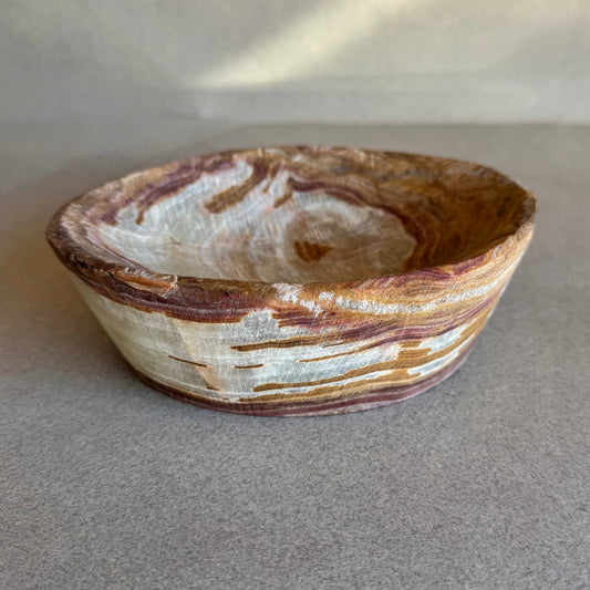Hand-carved onyx catchall bowl in sand, terracotta, blush, and ivory tones on neutral background