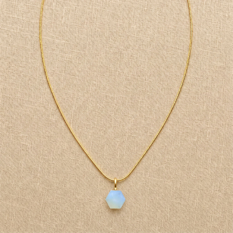 Hand wire-wrapped pale blue opalite hexagon pendant on gold-filled snake chain, lifestyle shot on model with sleek updo
