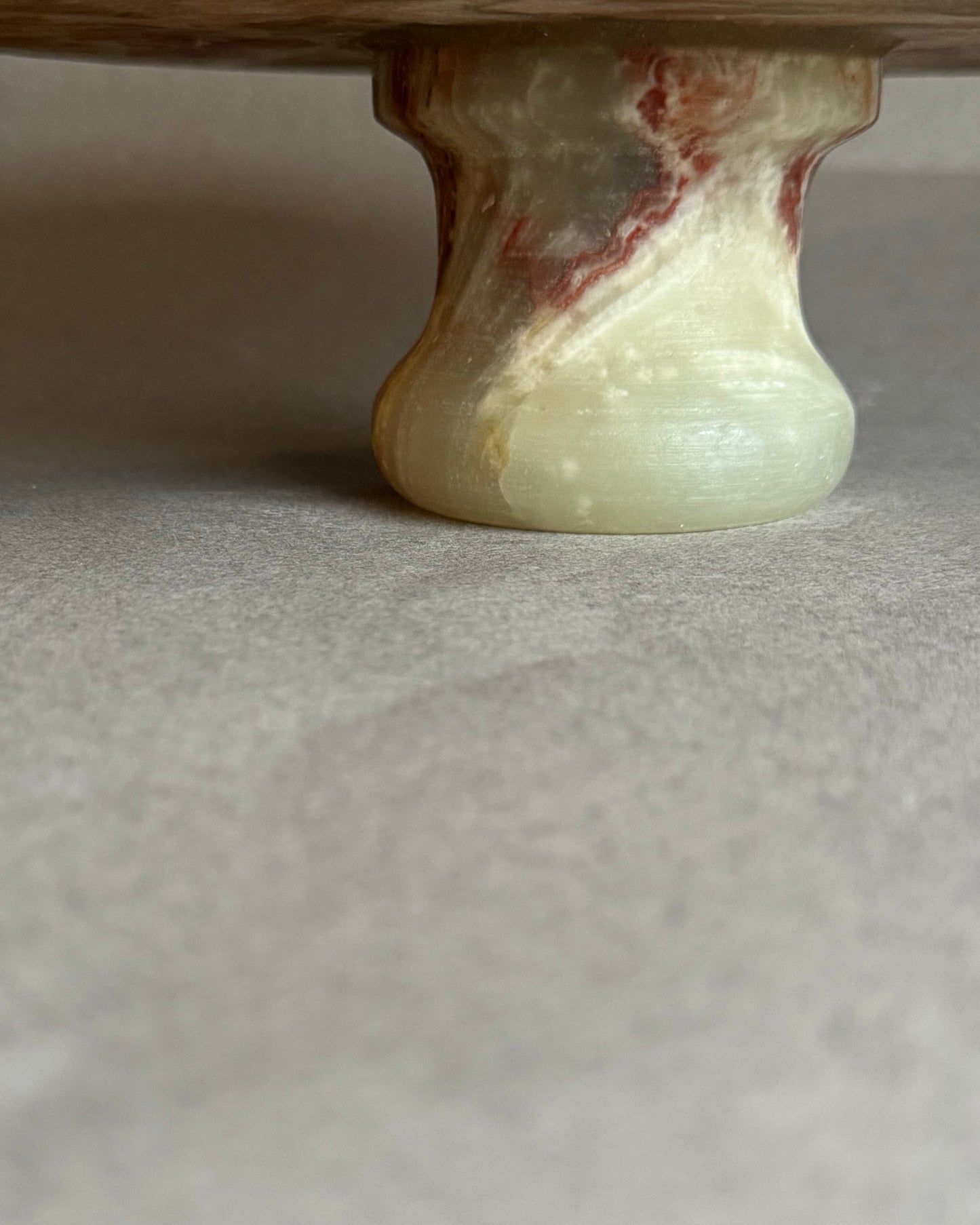 Close-up of a marble-like pedestal base on a neutral background