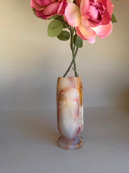 Decorative pink onyx vase with pink and white flowers on a plain background