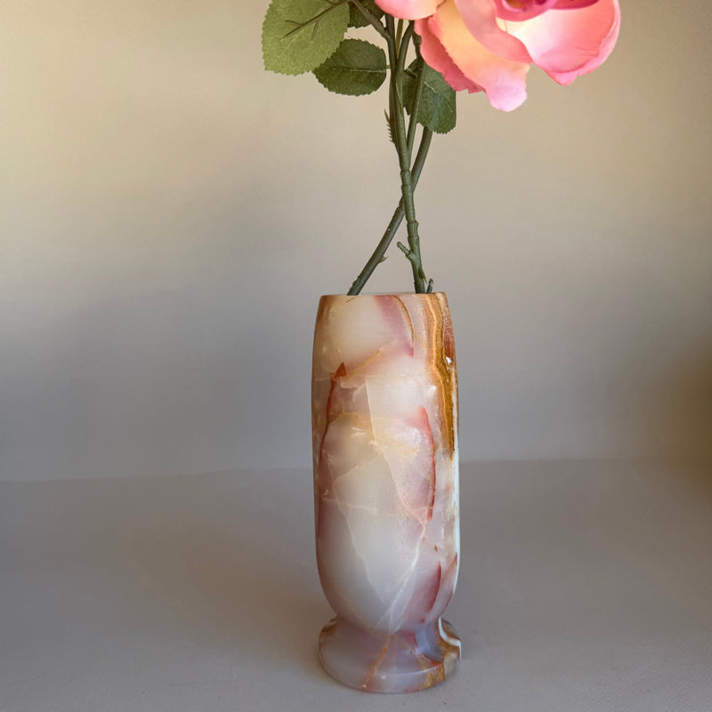 Decorative pink onyx vase with pink and white flowers on a plain background
