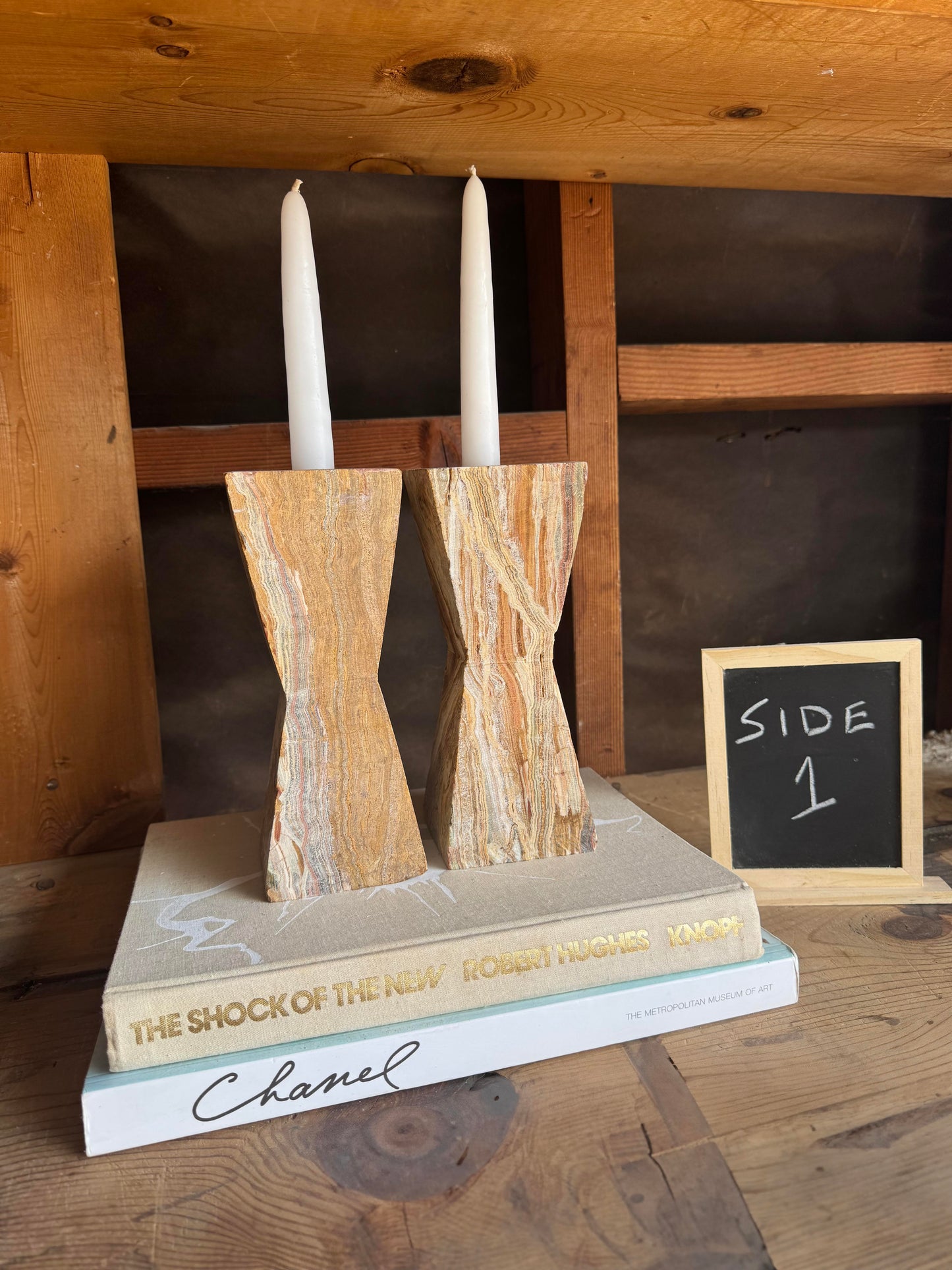 "Hand-carved onyx candle holders in warm earth tones – Side 2 view with taper candles on styled stack"

