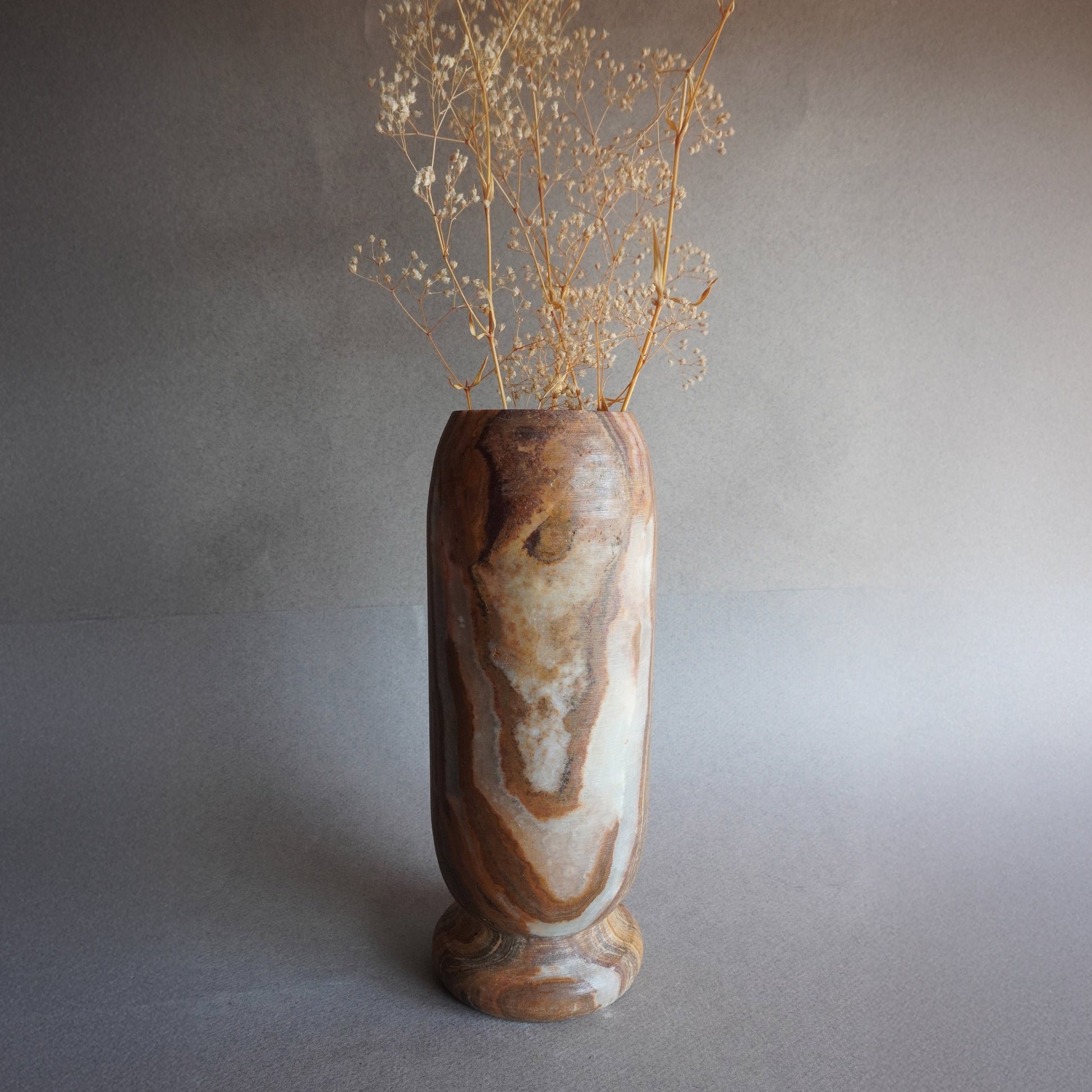 Hand-carved tall onyx vase in earth brown, ivory, and golden rust tones, sculptural stone vessel for flowers or home decor
