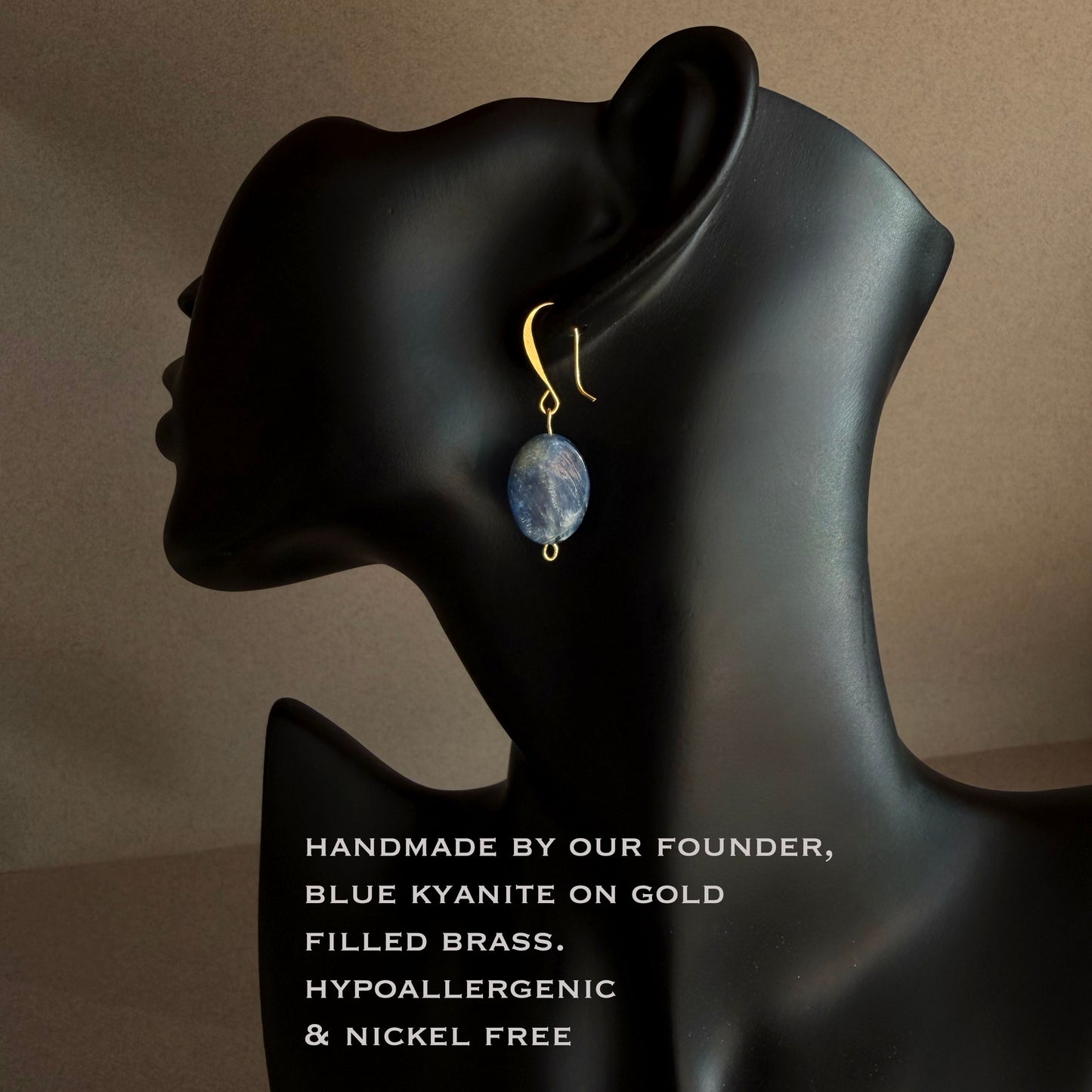 Natural blue kyanite oval stone earring with subtle striations, nickel free gold filled hook
 Earring on a black mannequin ear with text about the earring's material and features.