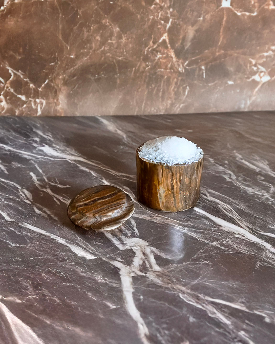 Two wooden containers with a textured surface on a marble countertop.