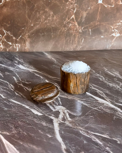 Two wooden containers with a textured surface on a marble countertop.