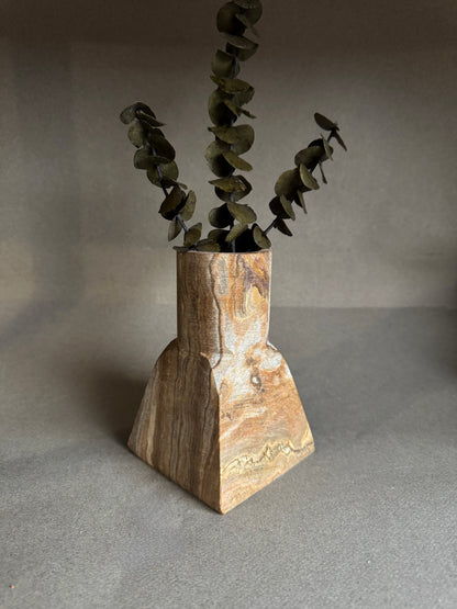 Stone vase with dried plant on a gray background