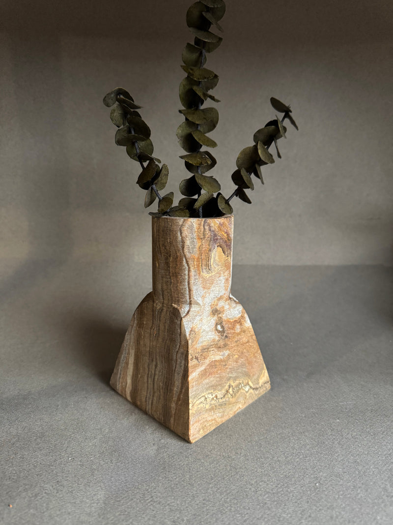 Stone vase with dried plant on a gray background