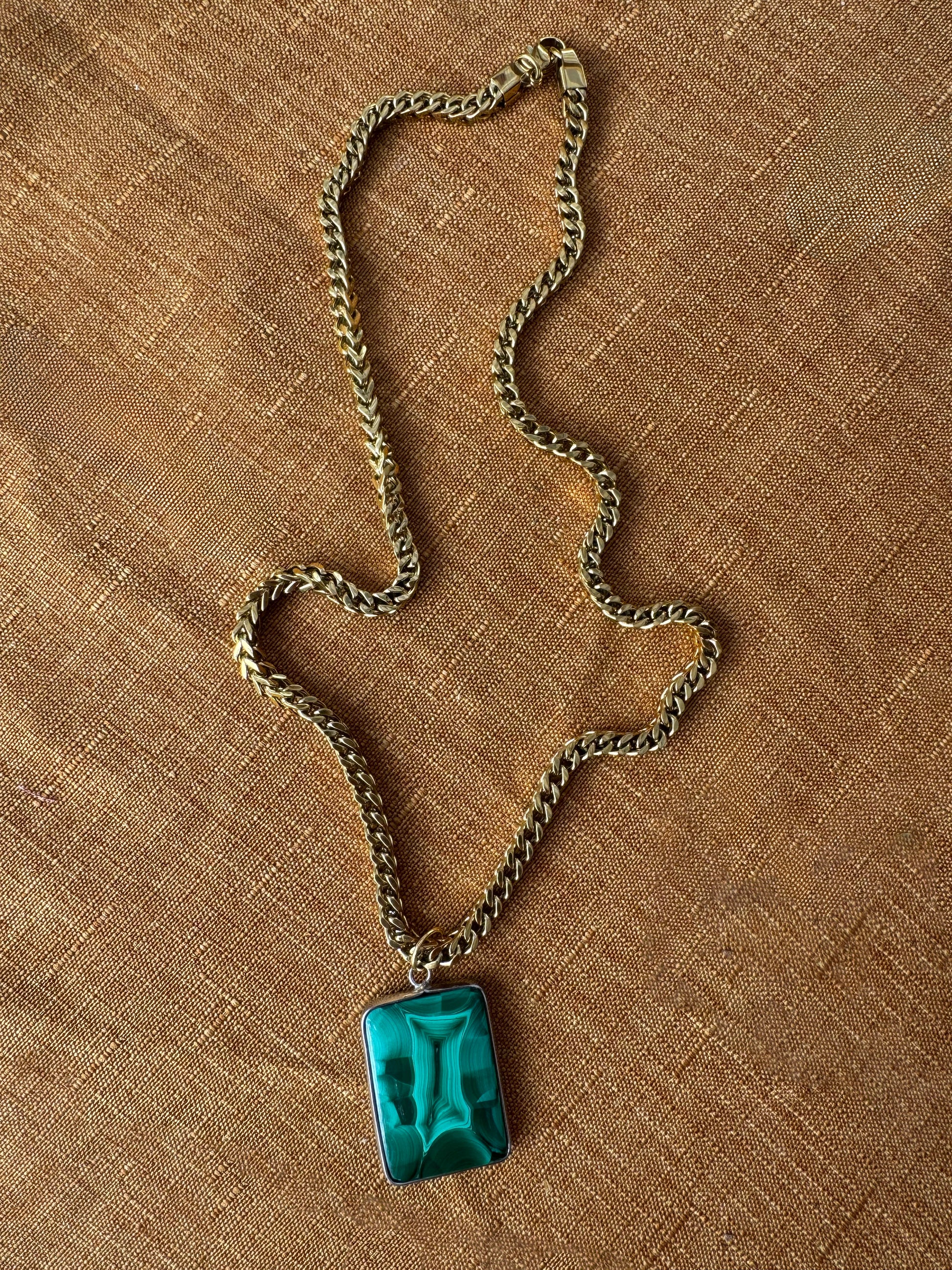 chunky Franco necklace with a green malachite pendant on a brown textured surface