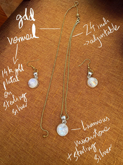 Gold vermeil moonstone pendant necklace and earrings on a brown fabric background with text describing features.