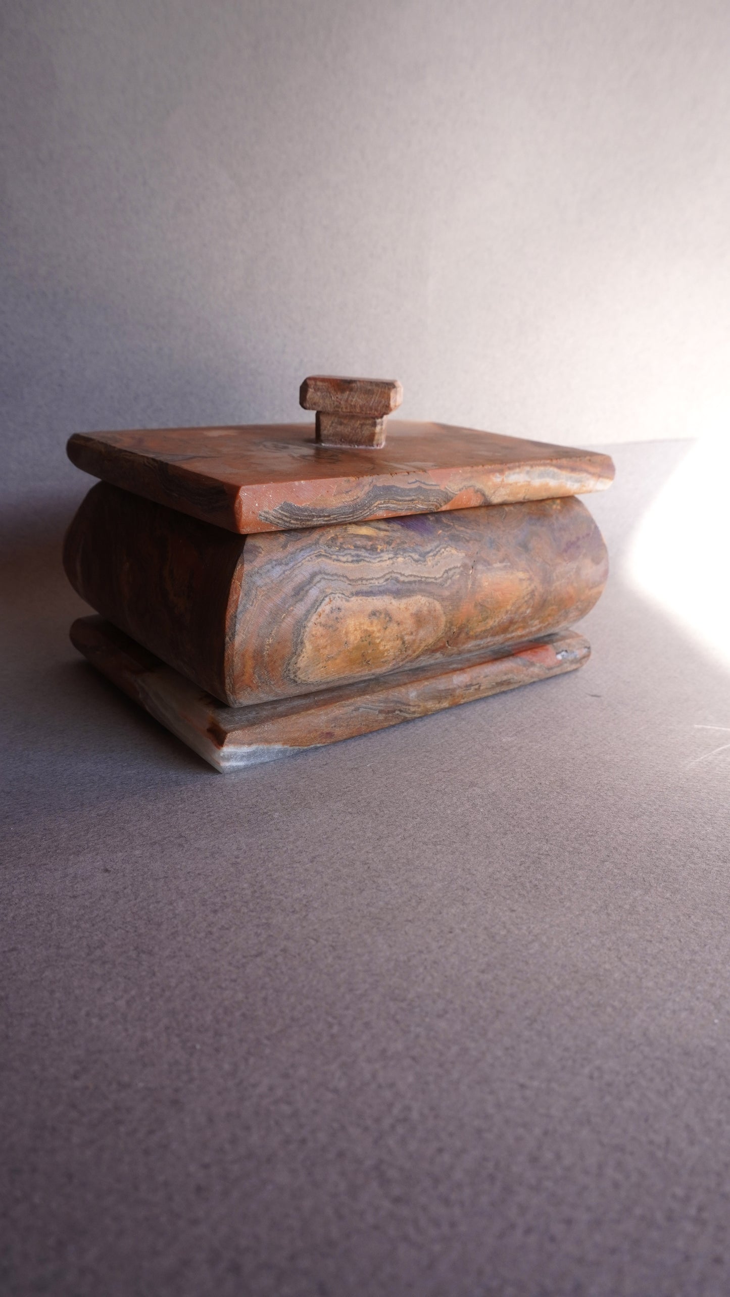 Rectangular sculptural onyx storage box with warm brown and amber veining  
