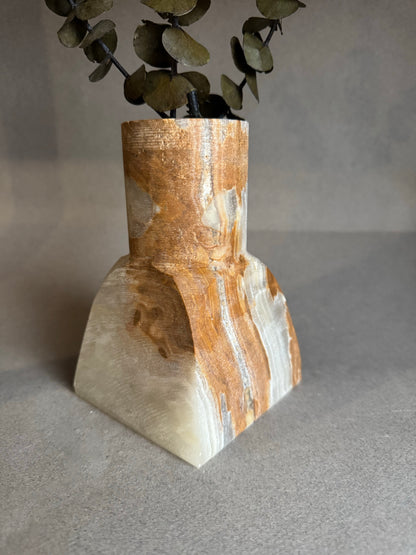Decorative vase with a textured surface and eucalyptus leaves on a neutral background