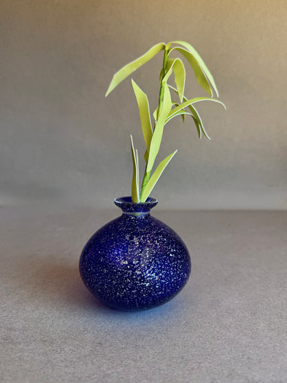 Blue speckled vase with a plant on a gray background