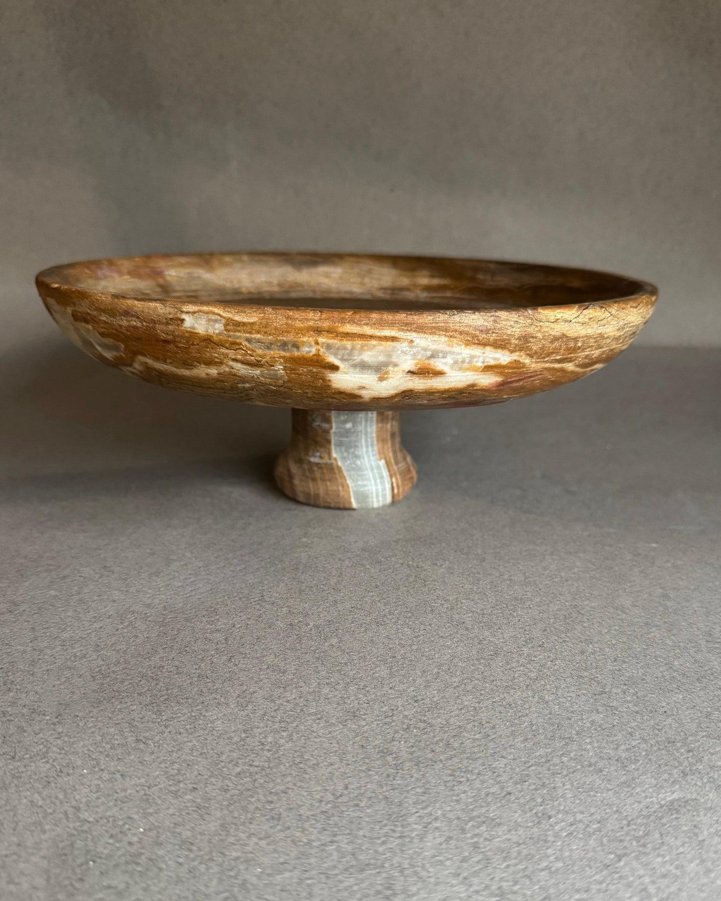 Wooden bowl with a pedestal base on a gray background