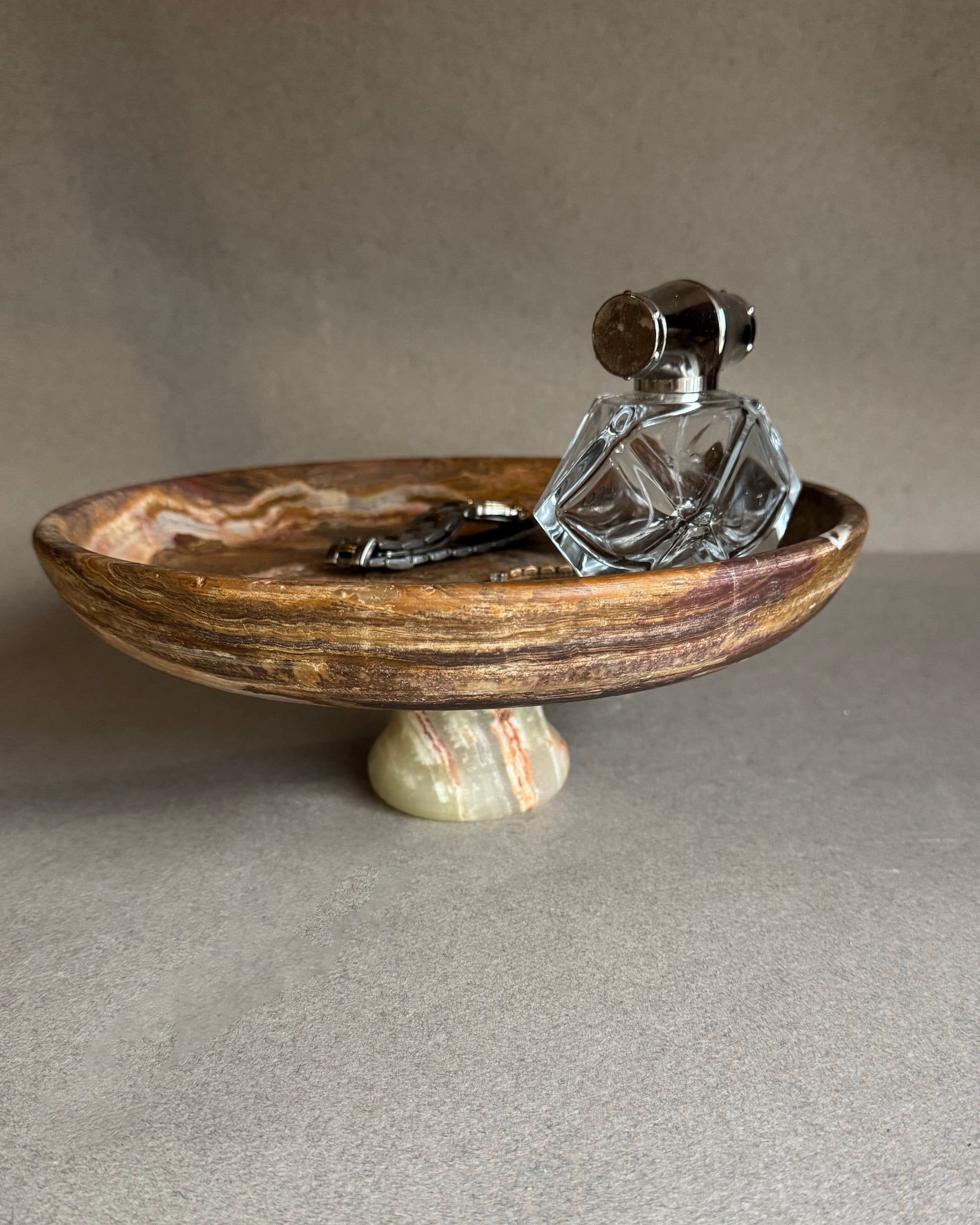 Decorative stone bowl with a crystal decanter on a neutral background