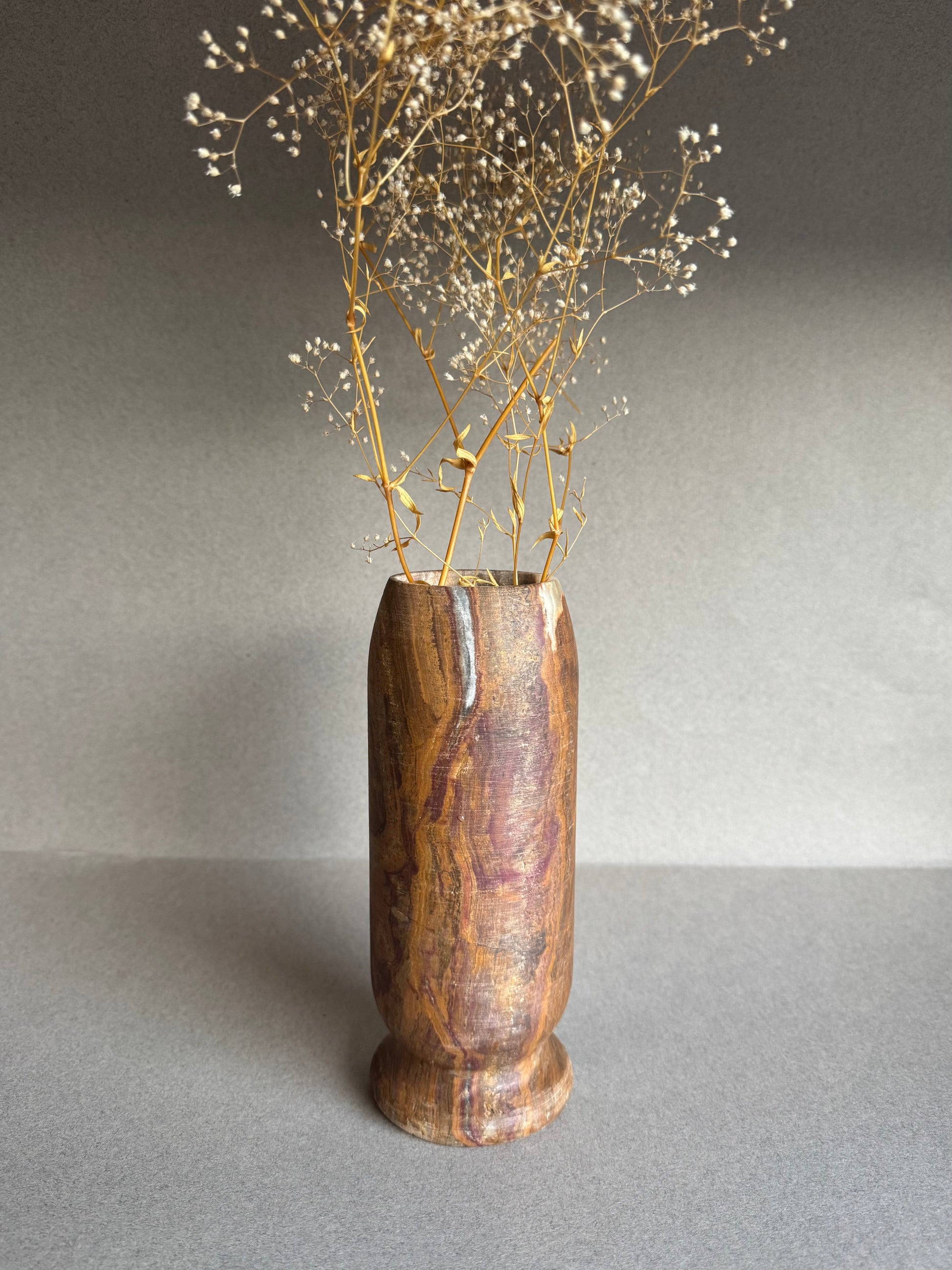 Hand-carved onyx vase in ochre, clay, and plum tones with dried florals