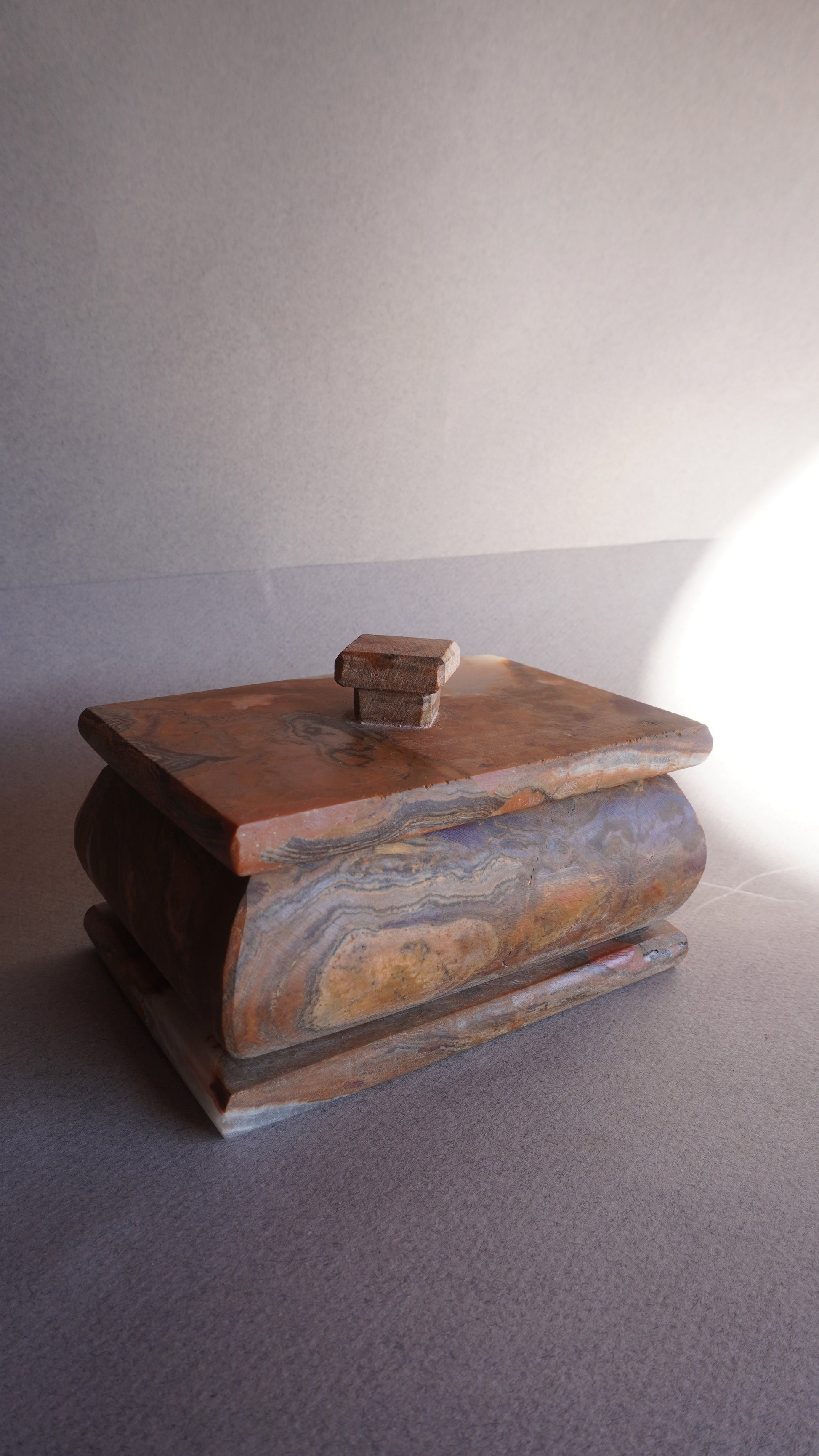 Small decorative stone box with lid, handcrafted from natural onyx for home decor  
