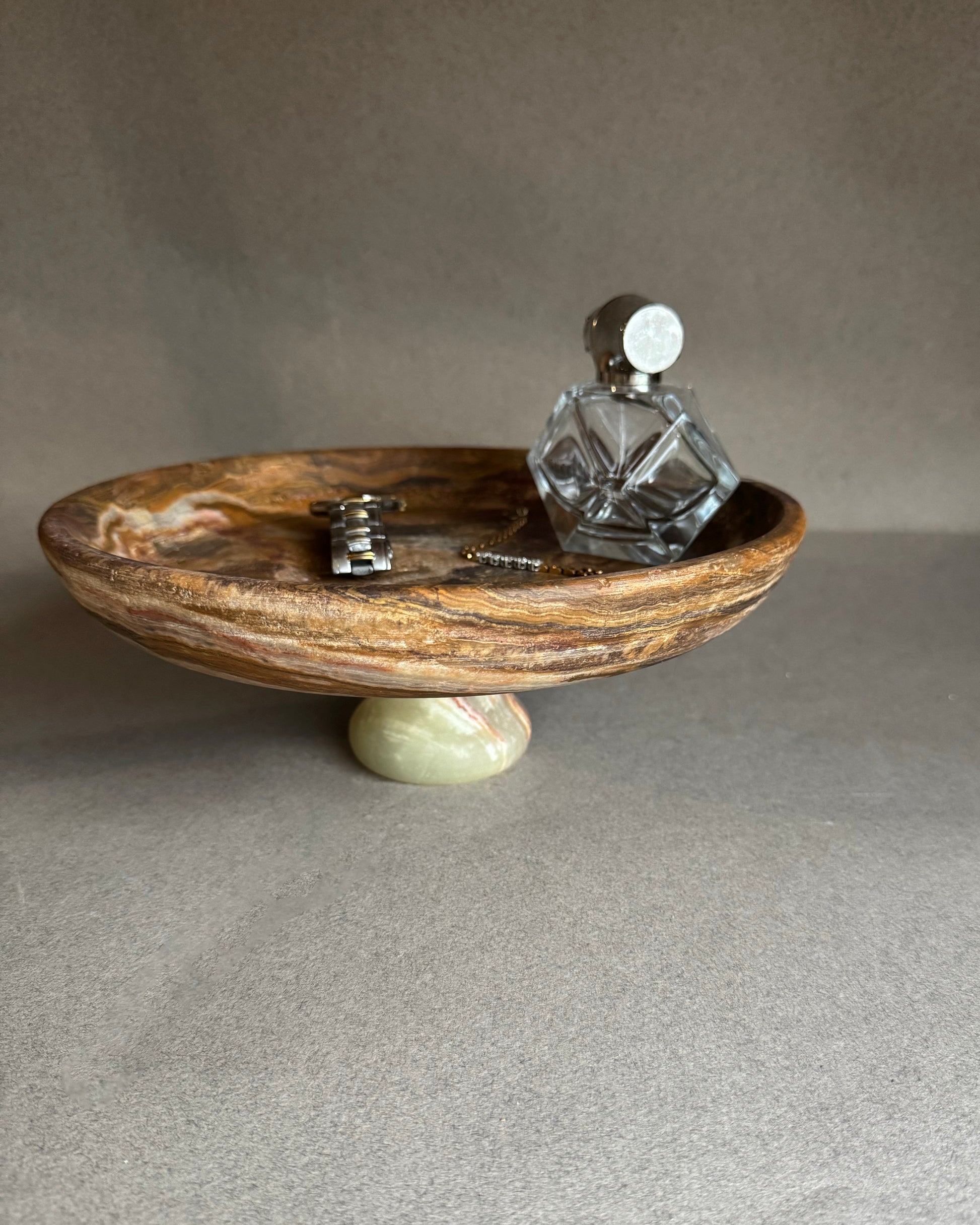 Decorative stone bowl with a small bottle and keys on a gray surface