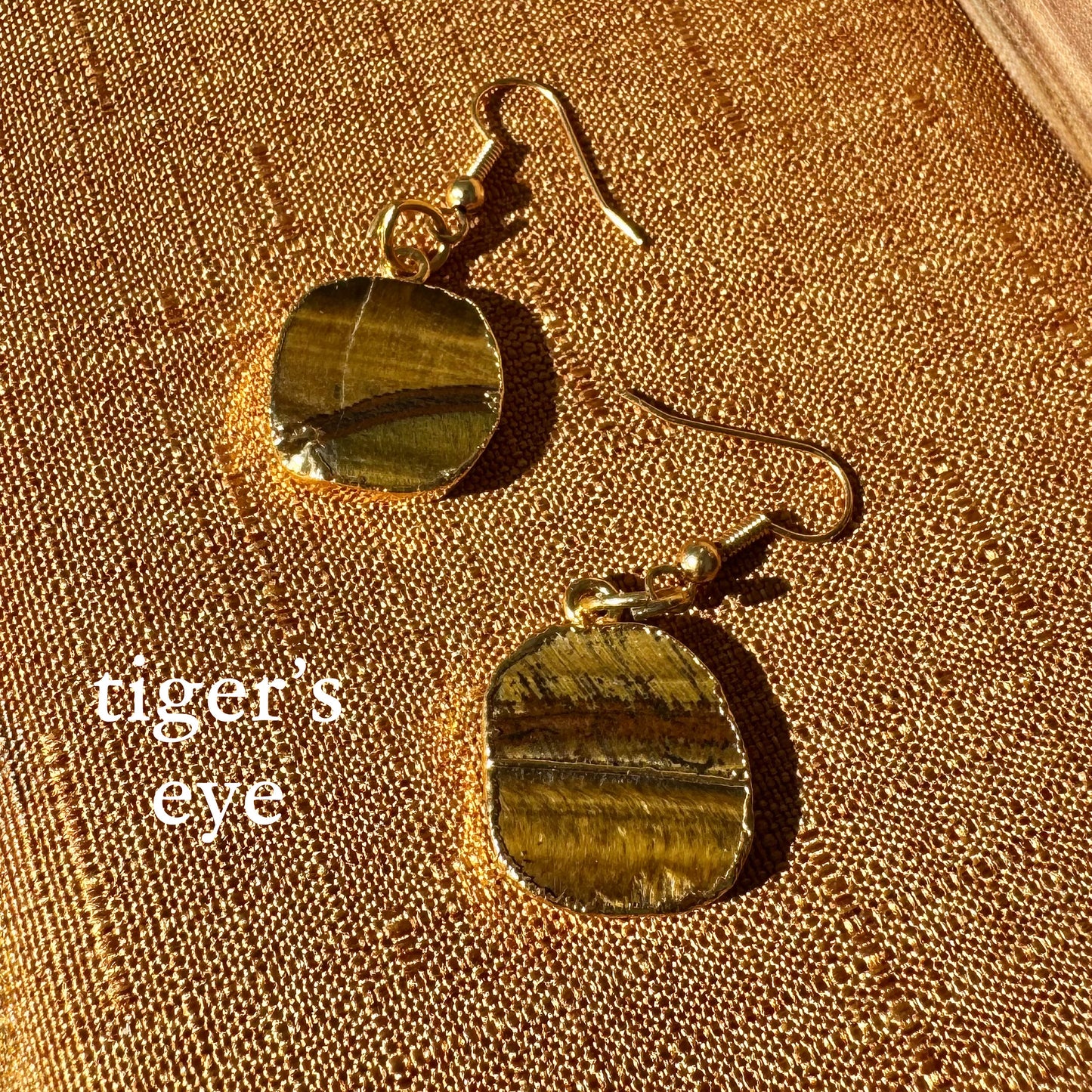 Tiger's eye earrings on a textured gold surface