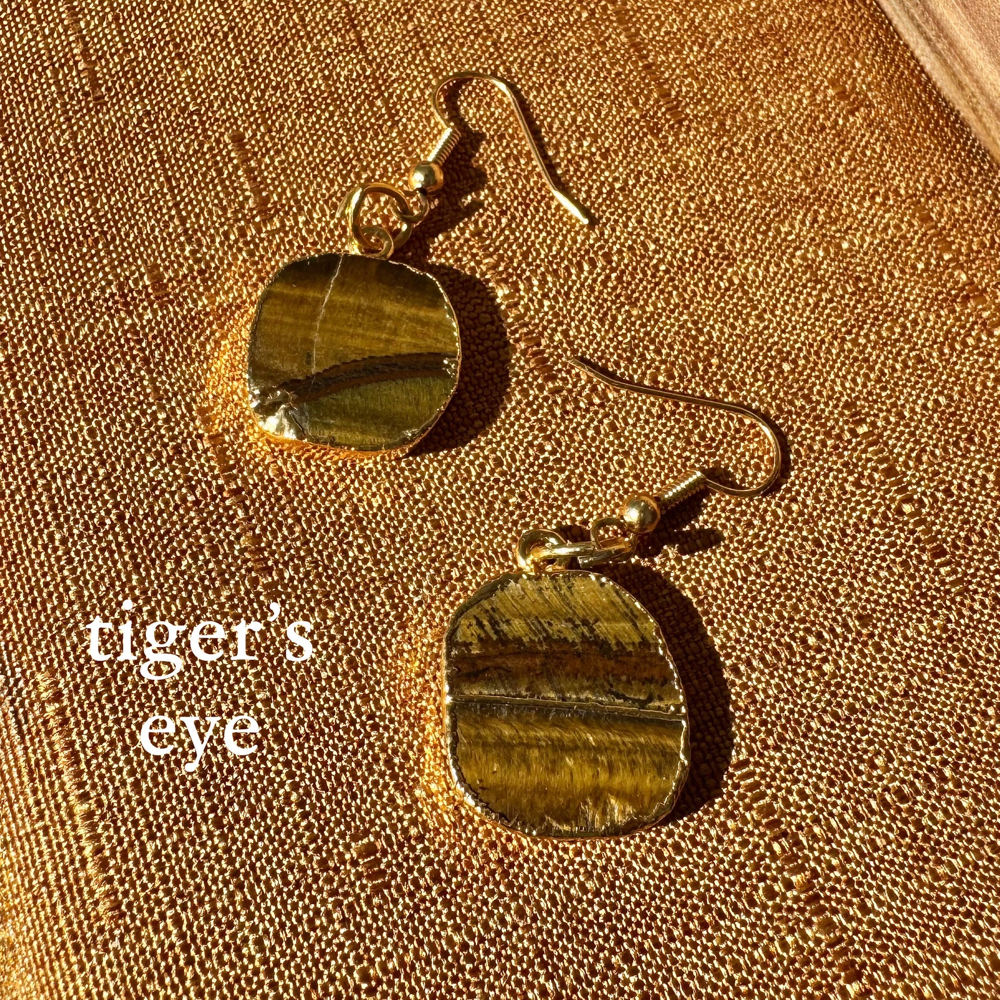 Tiger's eye earrings on a textured gold surface
