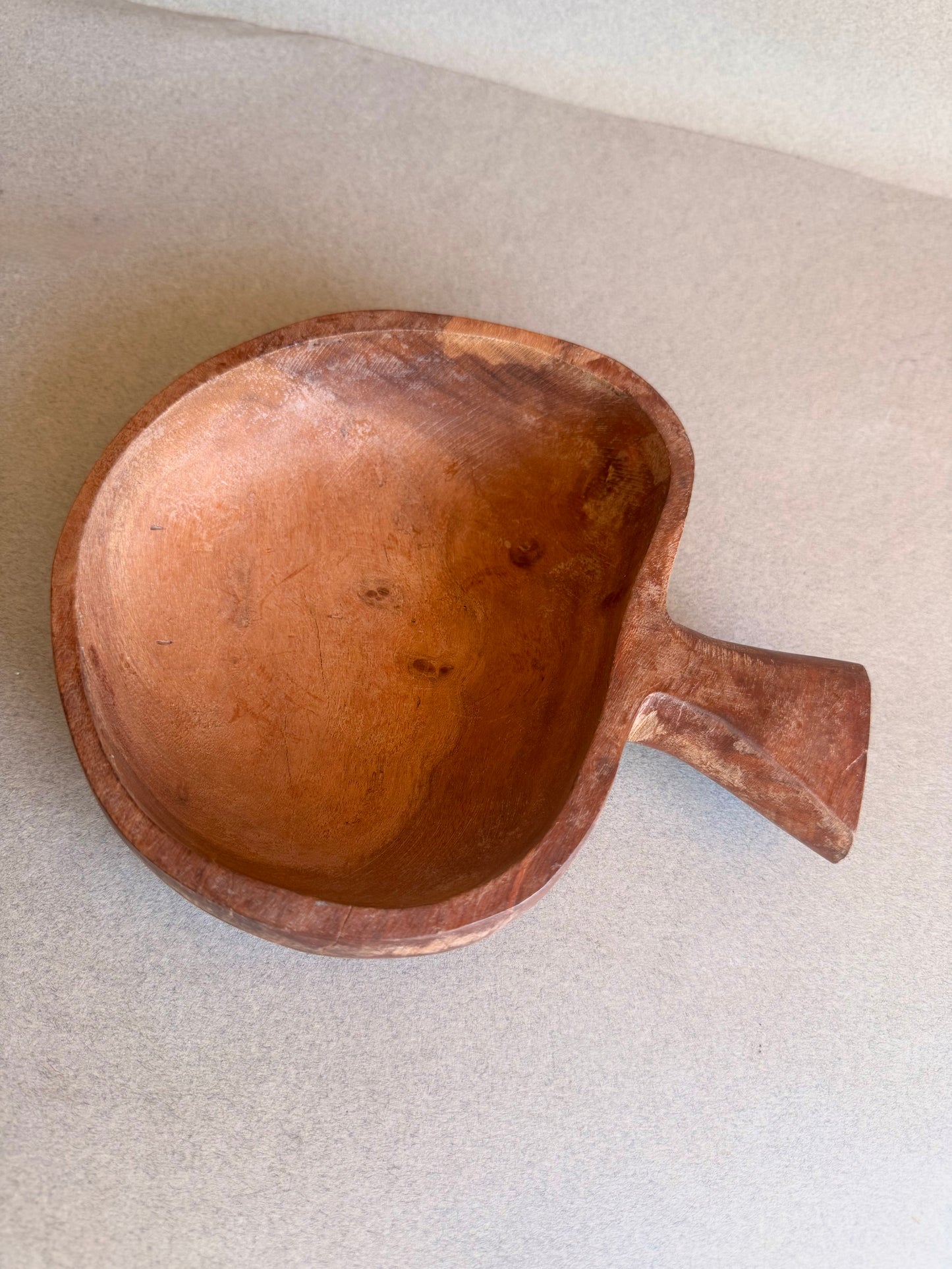 Brown ceramic bowl with a handle on a light gray background