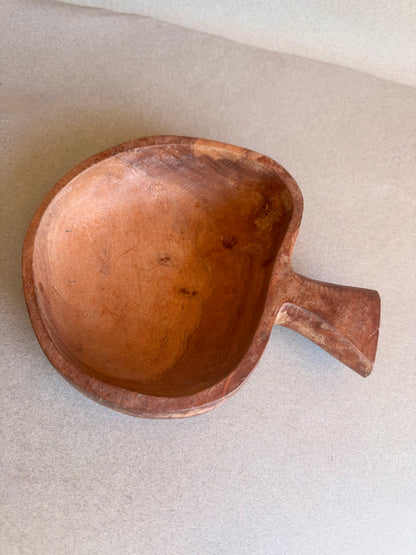 Brown ceramic bowl with a handle on a light gray background