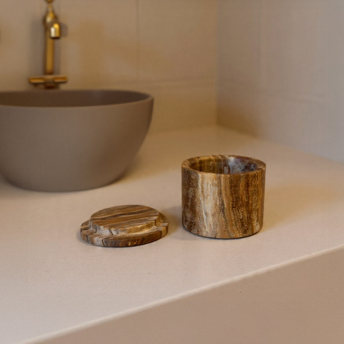 Wooden items on a bathroom counter with a sink in the background