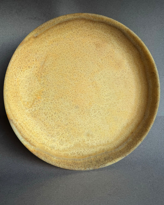 Round ceramic plate with a textured surface on a gray background