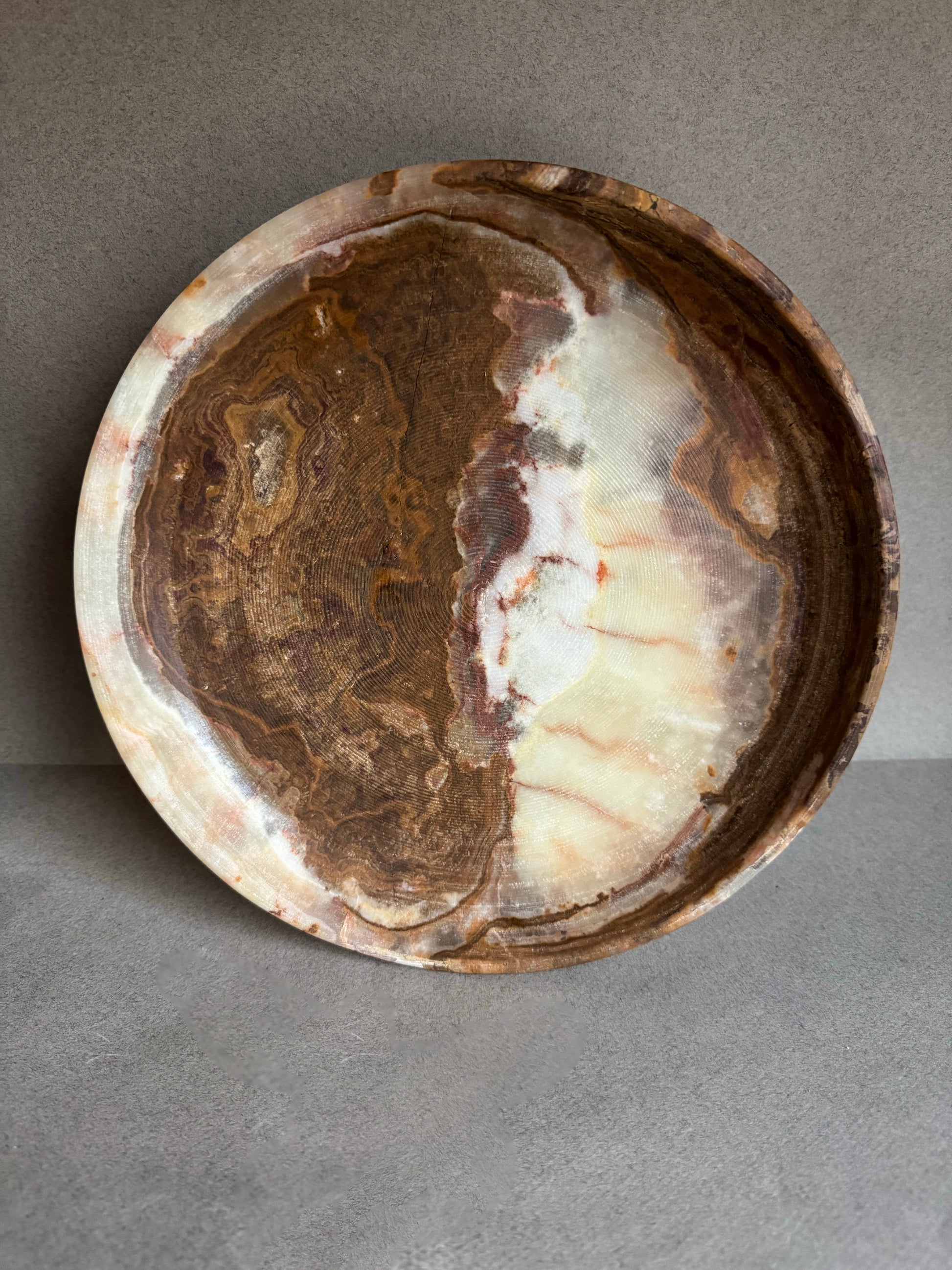 Round stone onxy dish with a textured surface on a gray background