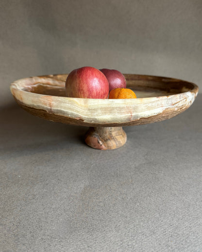 Onyx stone pedestal bowl with fruits on a gray background
