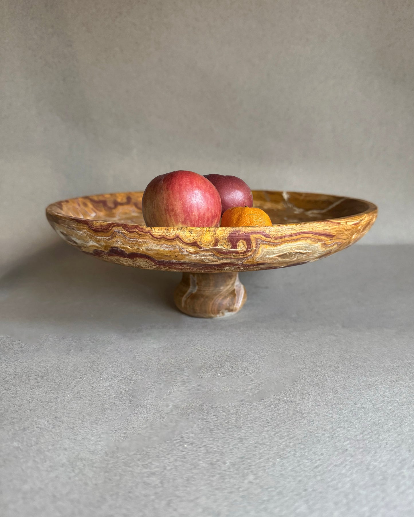 Stone bowl with apples on a gray surface