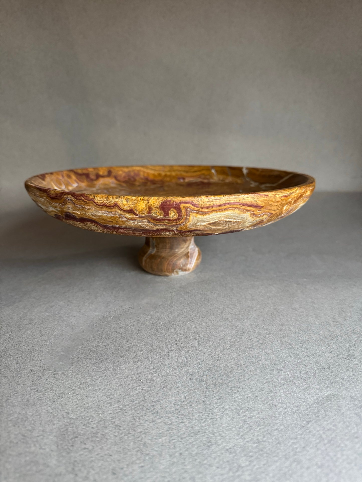 Decorative stone pedestal dish on a gray background