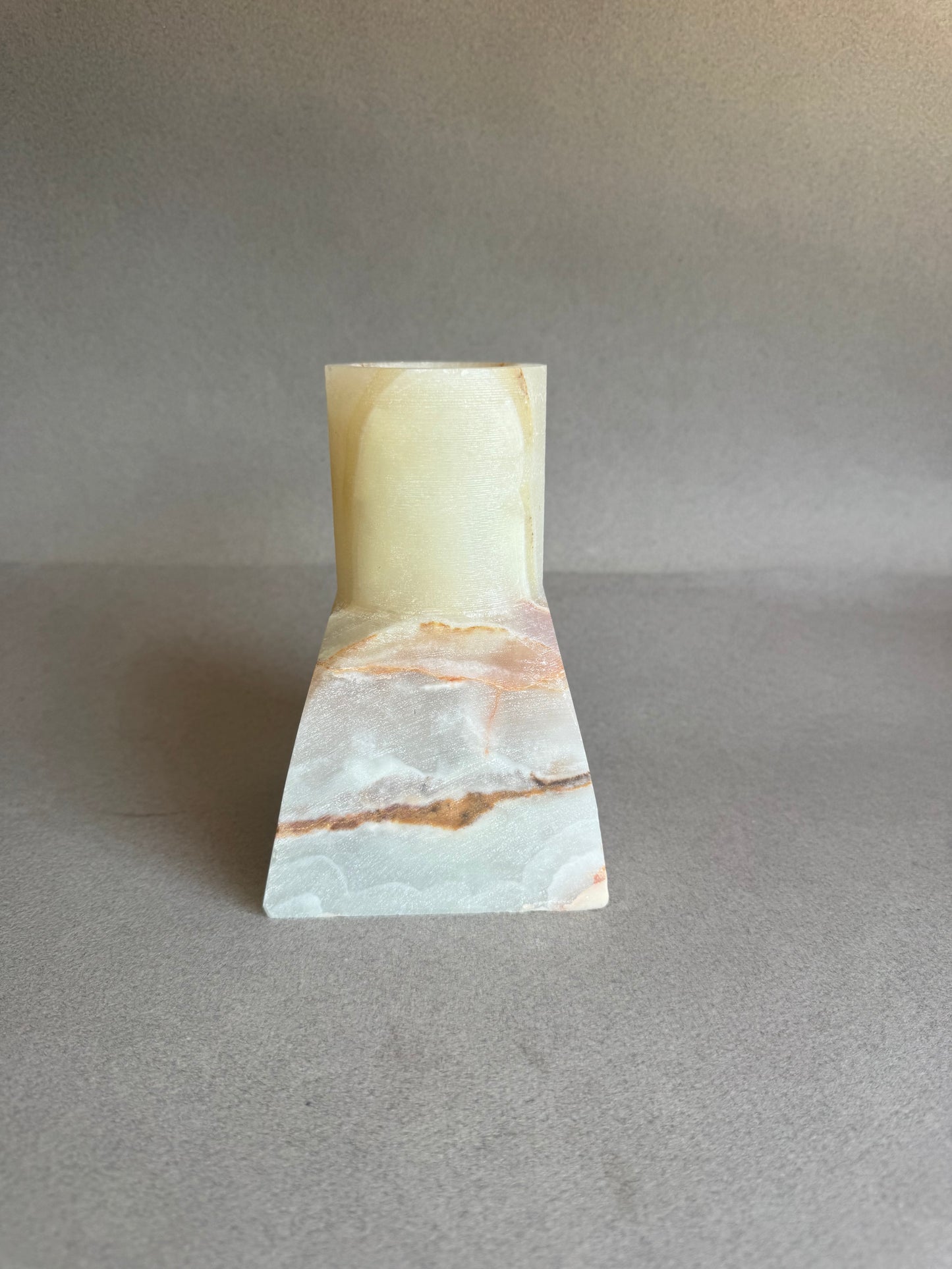 Marble-patterned onyx stone vase on a gray background