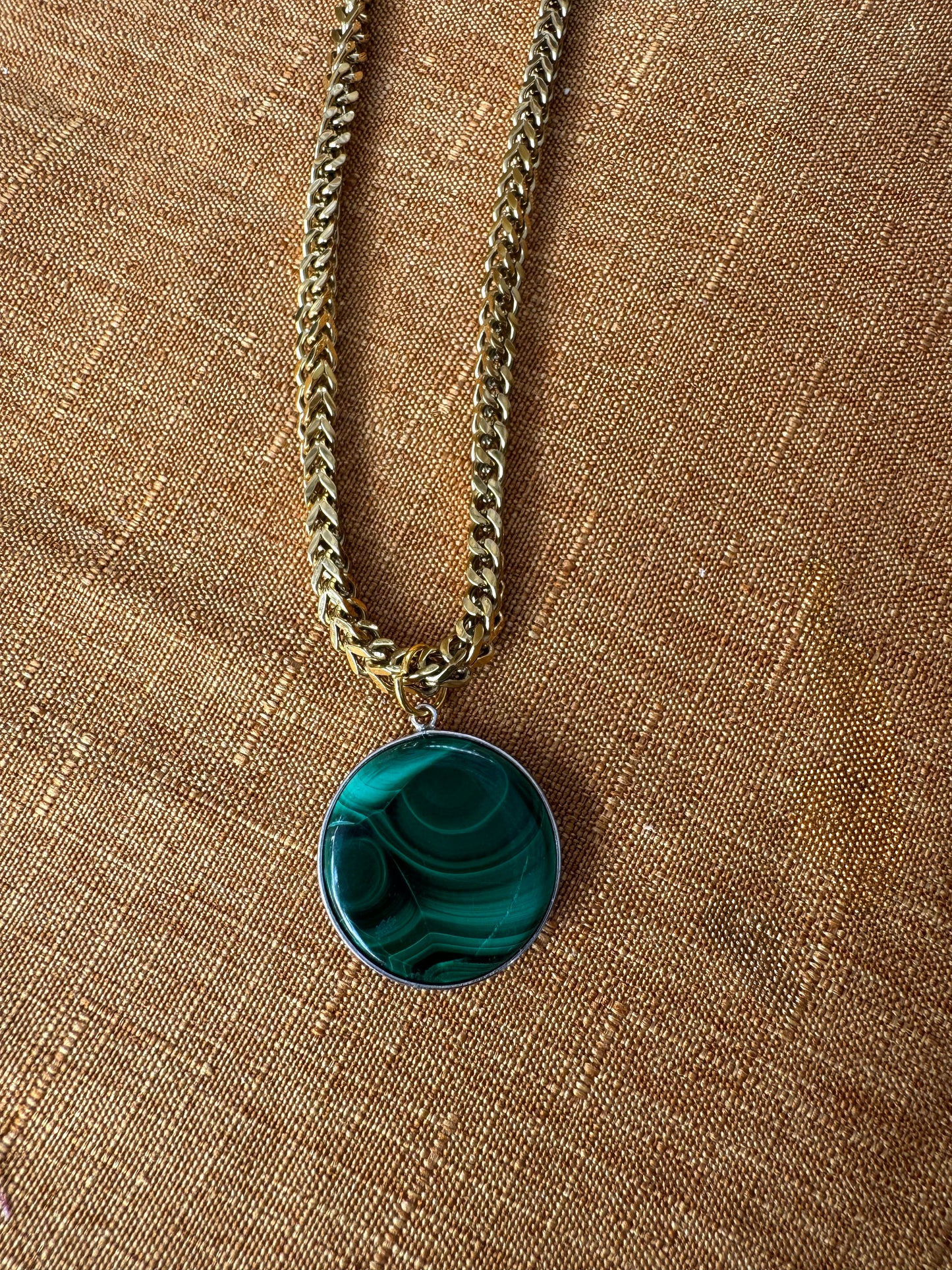 Necklace with a green pendant on a brown fabric background