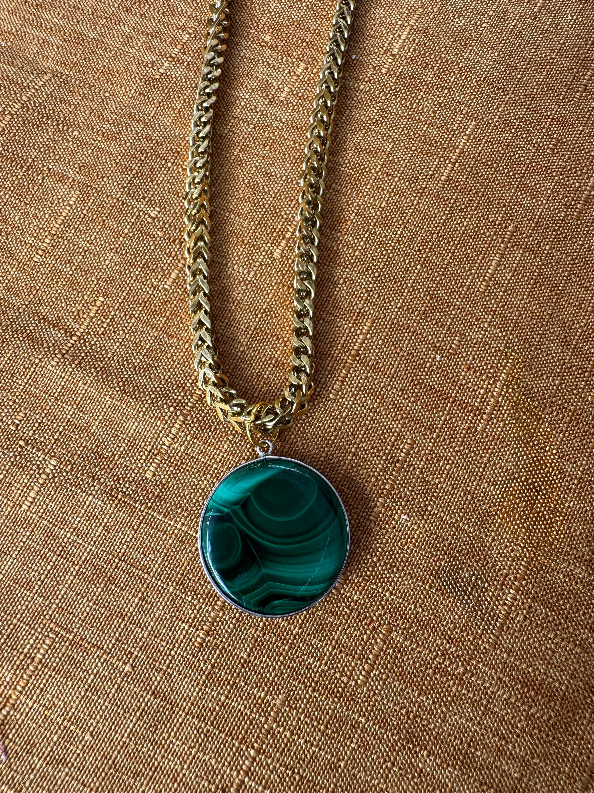 Necklace with a green pendant on a brown fabric background